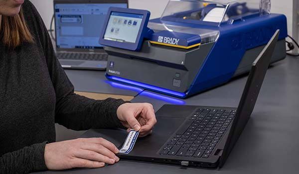 Addetto che applica un’etichetta per cespiti a un computer portatile.