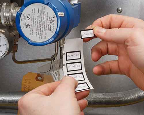 Operatore che applica etichette stampante dalla M610 su un macchinario.