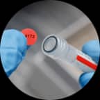 Etichetta rossa con testo stampato applicata sulla parte superiore di una provetta di colore corrispondente.