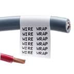 Primo piano di un’etichetta Brady wrap around su un cavo grigio. L’etichetta è bianca con testo nero ripetuto per facilitare il riconoscimento.