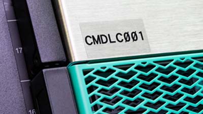 Componente di un macchinario con un’etichetta in poliestere trasparente con testo nero.