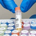 Tecnico di laboratorio che tiene in mano una provetta con due etichette con codice a barre.