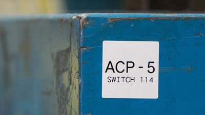 Etichetta bianca su un’apparecchiatura, con scritta 