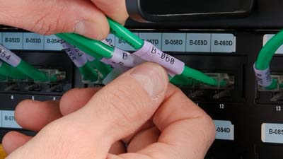 Etichetta wrap around in vinile autolaminante avvolta su un cavo Cat-5e verde.